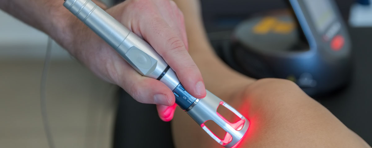 Clinician applying Class IV laser therapy to a patient's knee for osteoarthritis pain relief — ReliefNow Laser Centers